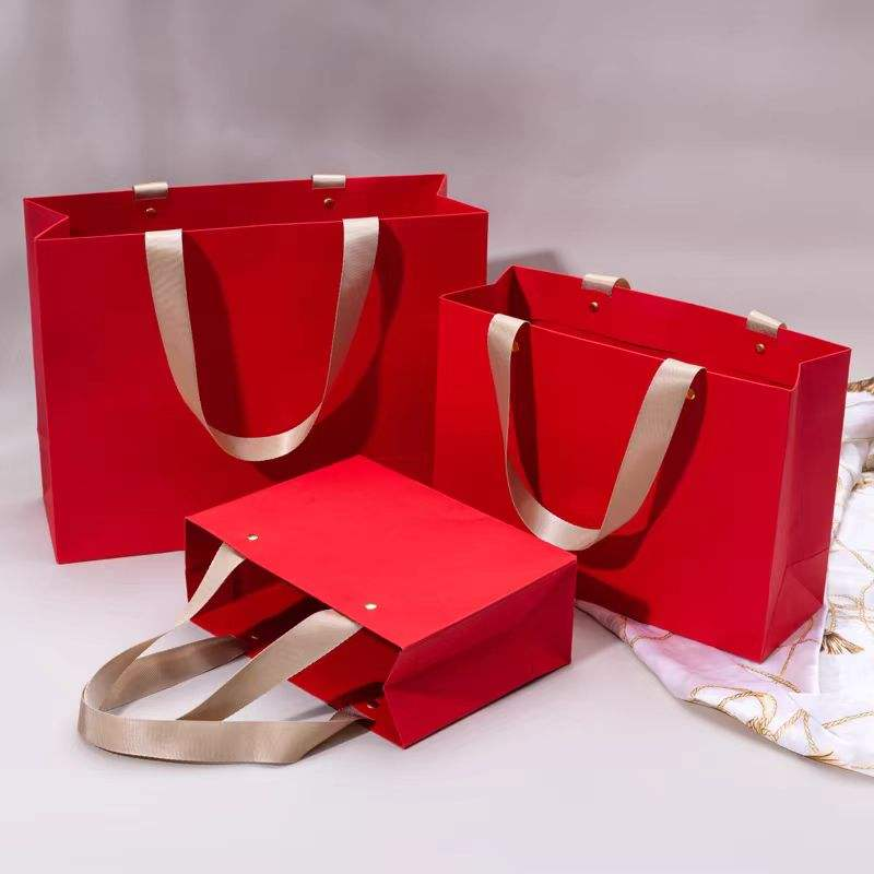 Red paper gift bags with ribbon handles reference